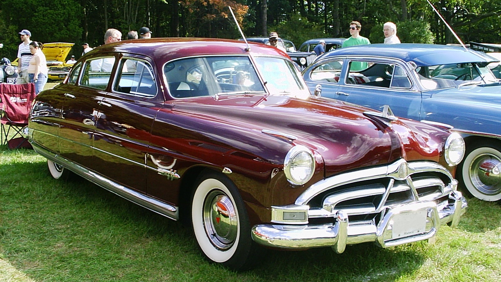 Hudson Hornet 1951 rouge bordeaux, type step-down, stationnée lors d'un rassemblement de voitures classiques.