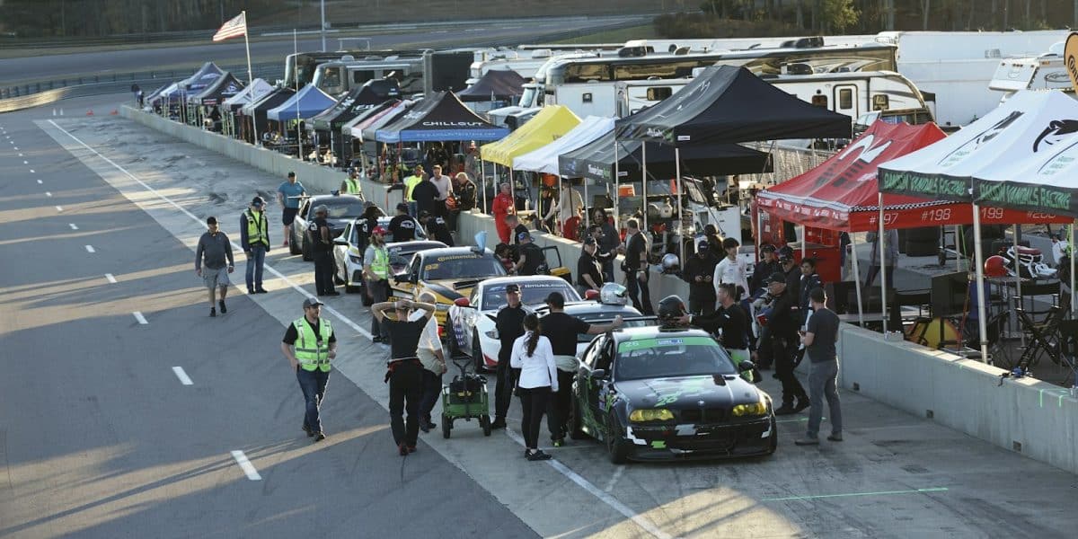 Paddock d’une journée de roulage sur circuit, voitures de sport alignées
