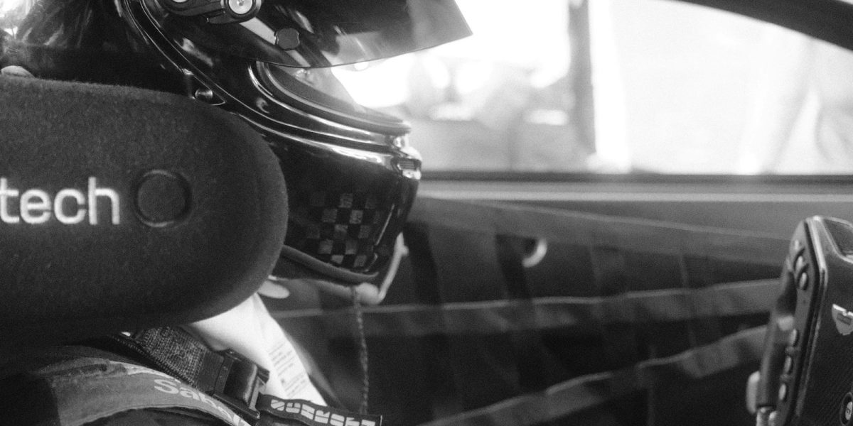 Pilote installé dans son baquet, mains sur le volant, en position de conduite sur circuit