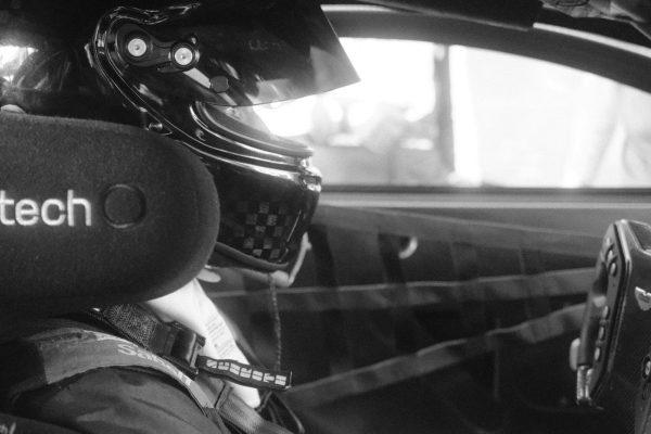 Pilote installé dans son baquet, mains sur le volant, en position de conduite sur circuit