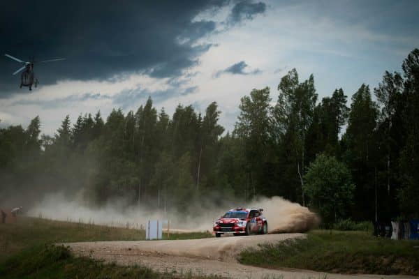 Voiture de rallye sur piste en terre au bord d'une forêt