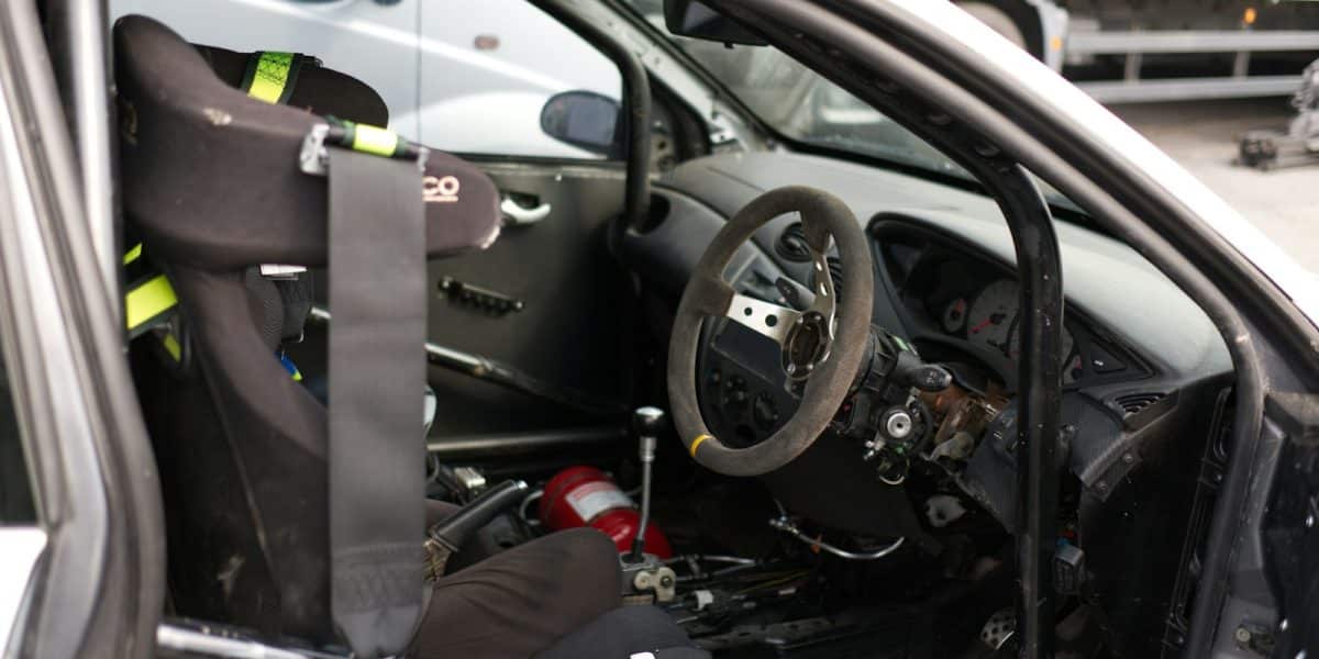 Intérieur d'une voiture de course : baquet, harnais, extincteur et arceau