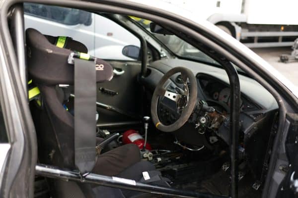 Intérieur d'une voiture de course : baquet, harnais, extincteur et arceau