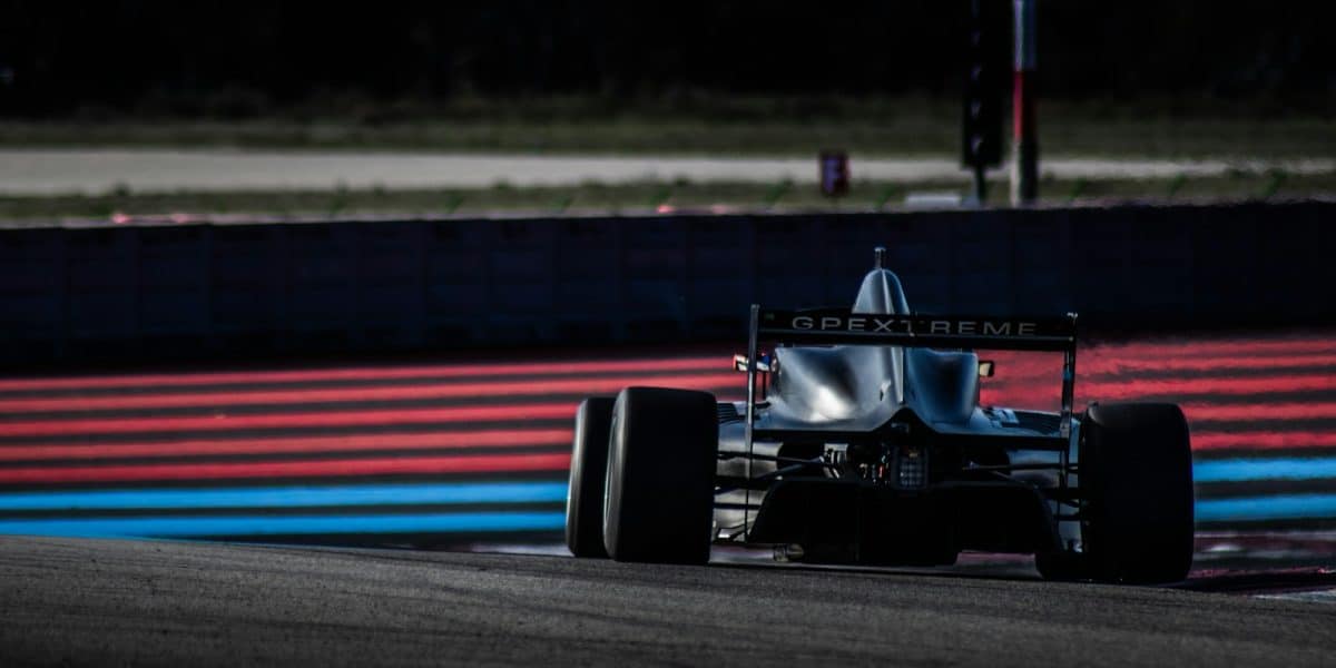 Monoplace en piste sur circuit, entre les bordures rouges et bleues