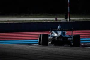 Monoplace en piste sur circuit, entre les bordures rouges et bleues