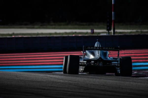 Monoplace en piste sur circuit, entre les bordures rouges et bleues